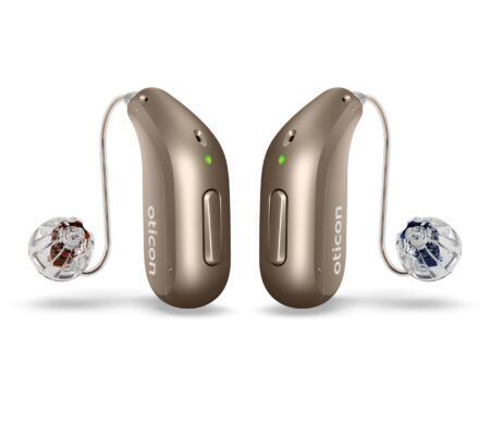 Tvö beige Oticon heyrnartæki, með gegnsæjum eyrnatappa og grænum stöðuljósum.