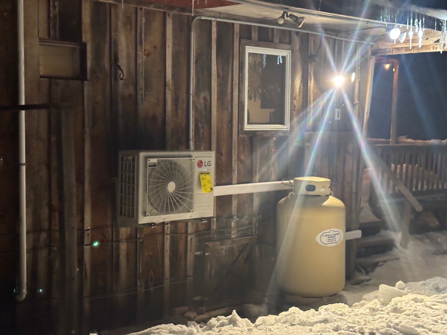 Top-down view of an outdoor air conditioning unit fan spinning behind a circular metal wire protective grate.