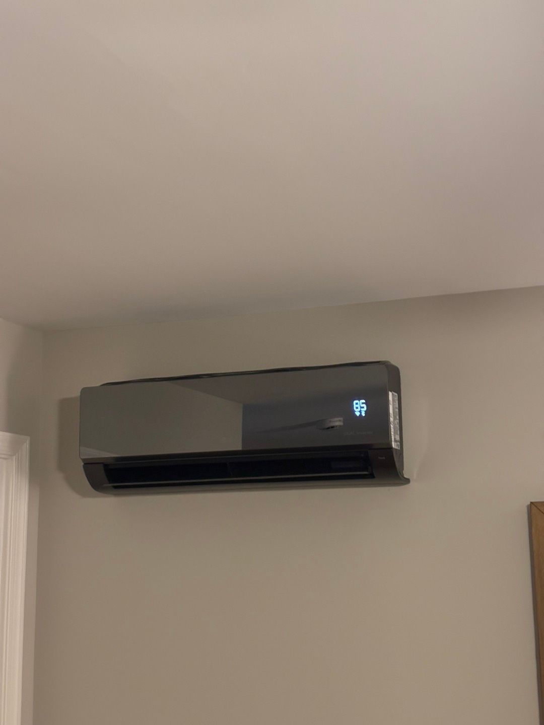 Multiple gray residential air conditioning units sit on concrete pads outside a home next to green landscaping.