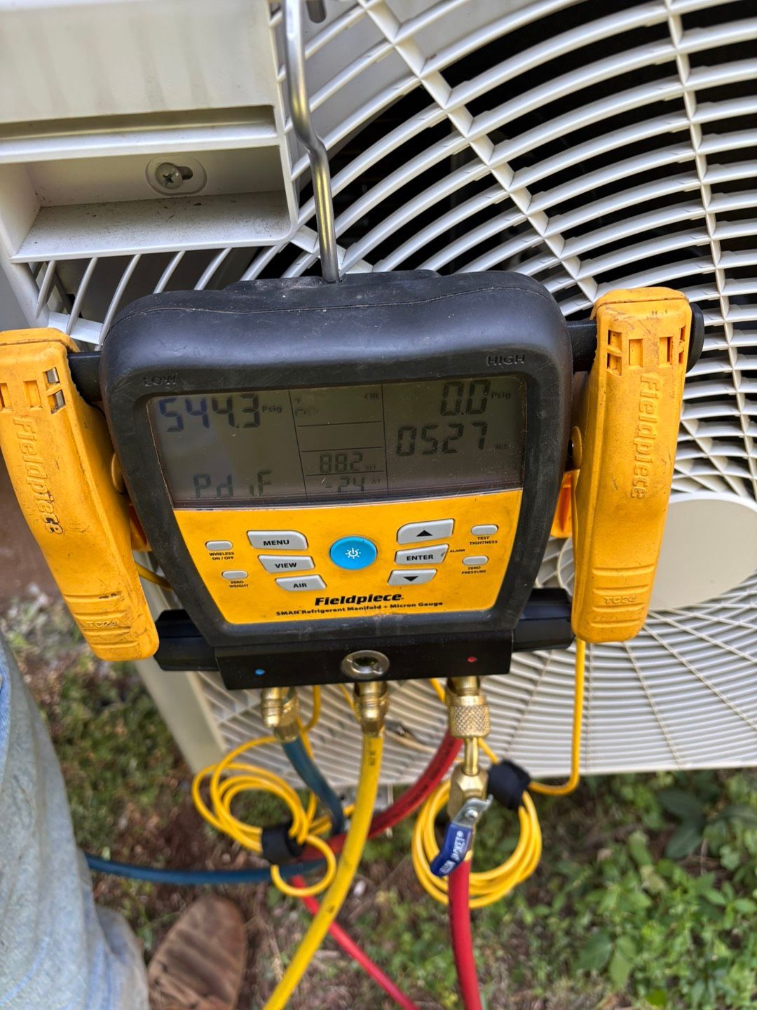 A technician installs or repairs a wall-mounted air conditioning unit in a white room.
