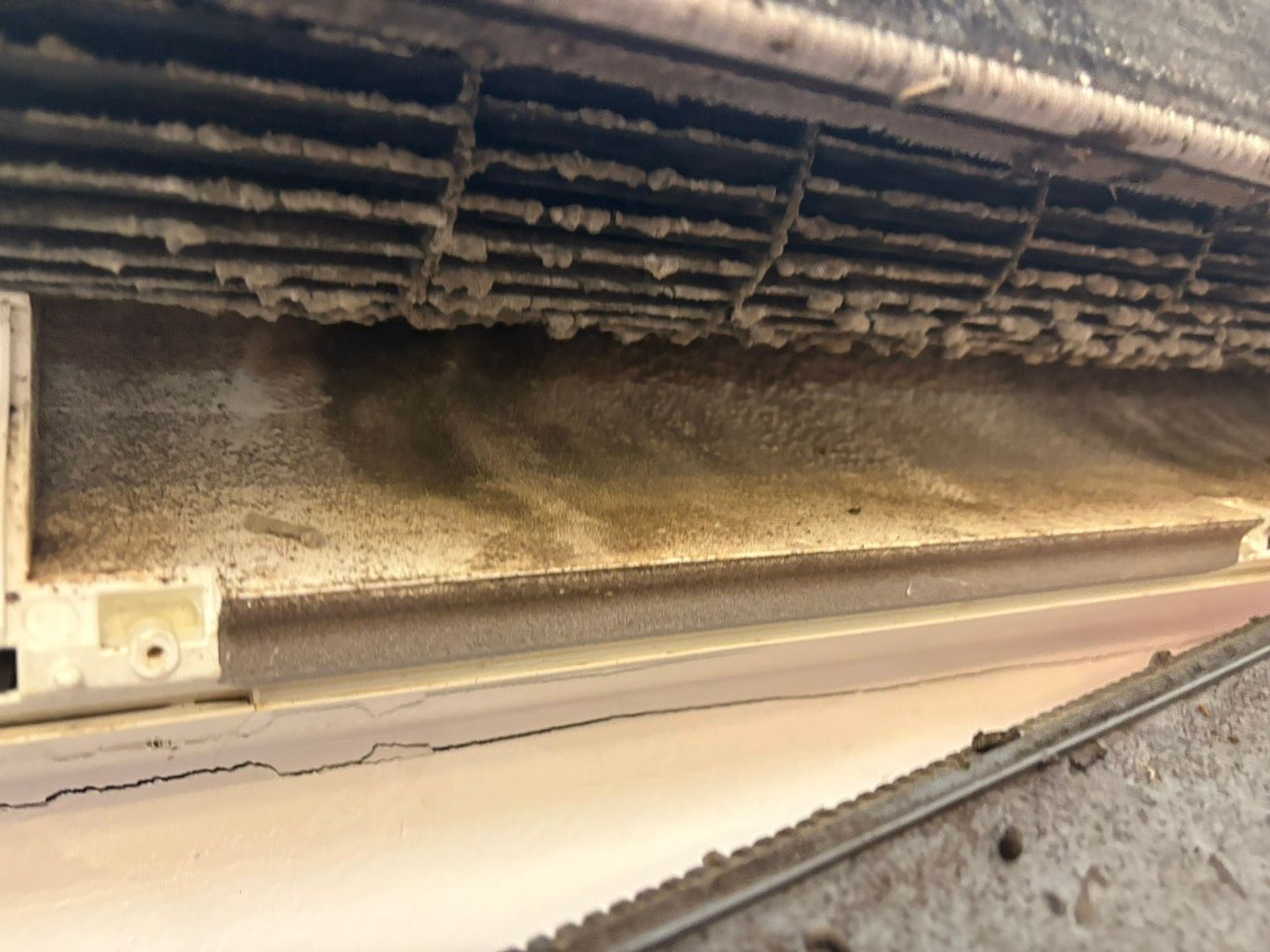 A white wall-mounted air conditioning unit blowing cool air into a room near a window.