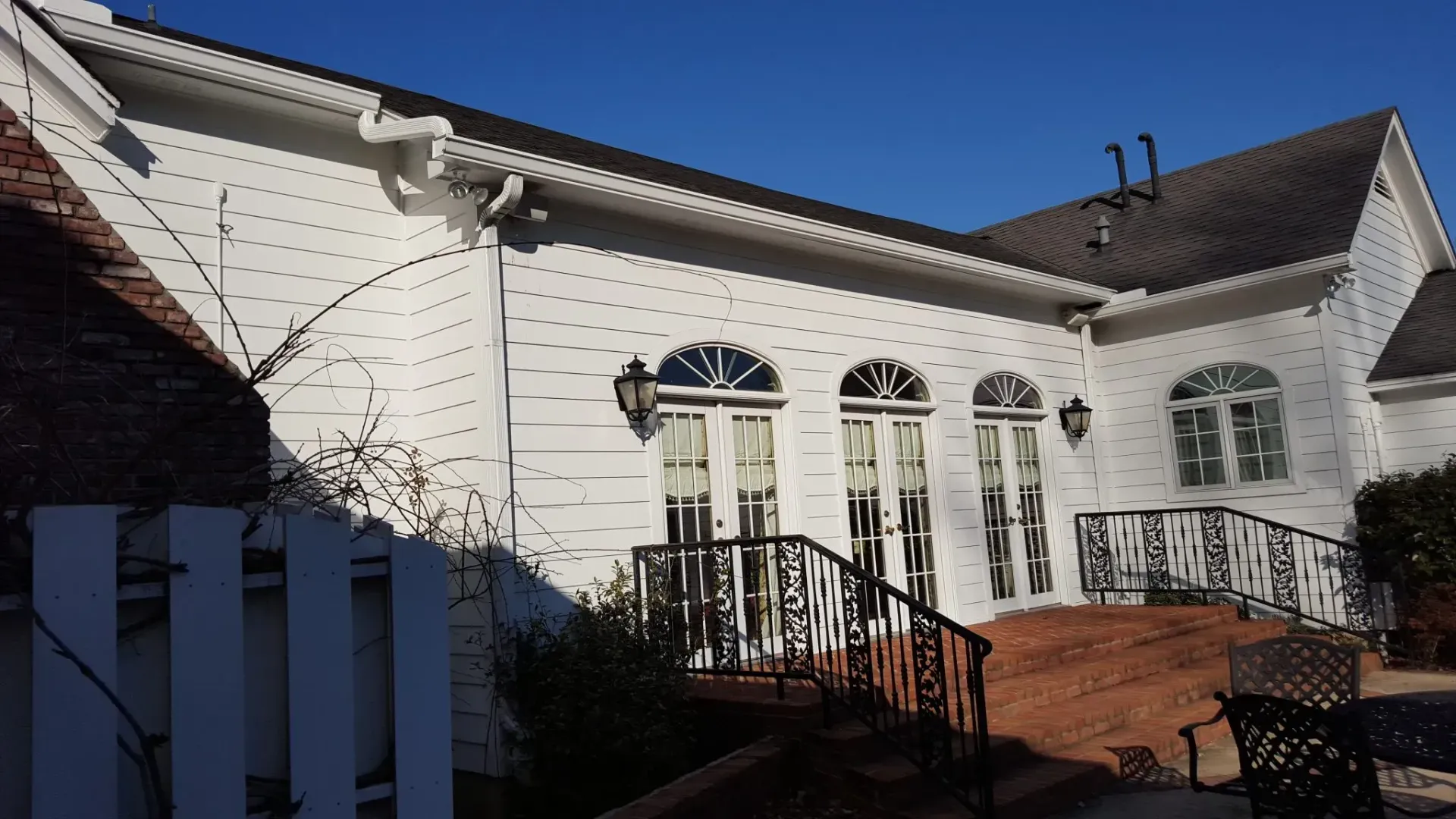 White brick building with arched windows and a wrought iron staircase.