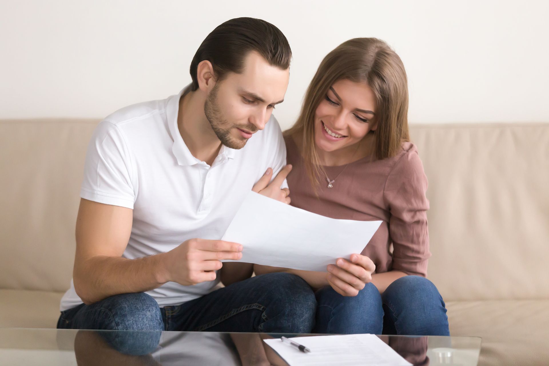 A couple sitting together on a couch, smiling as they review a loan document