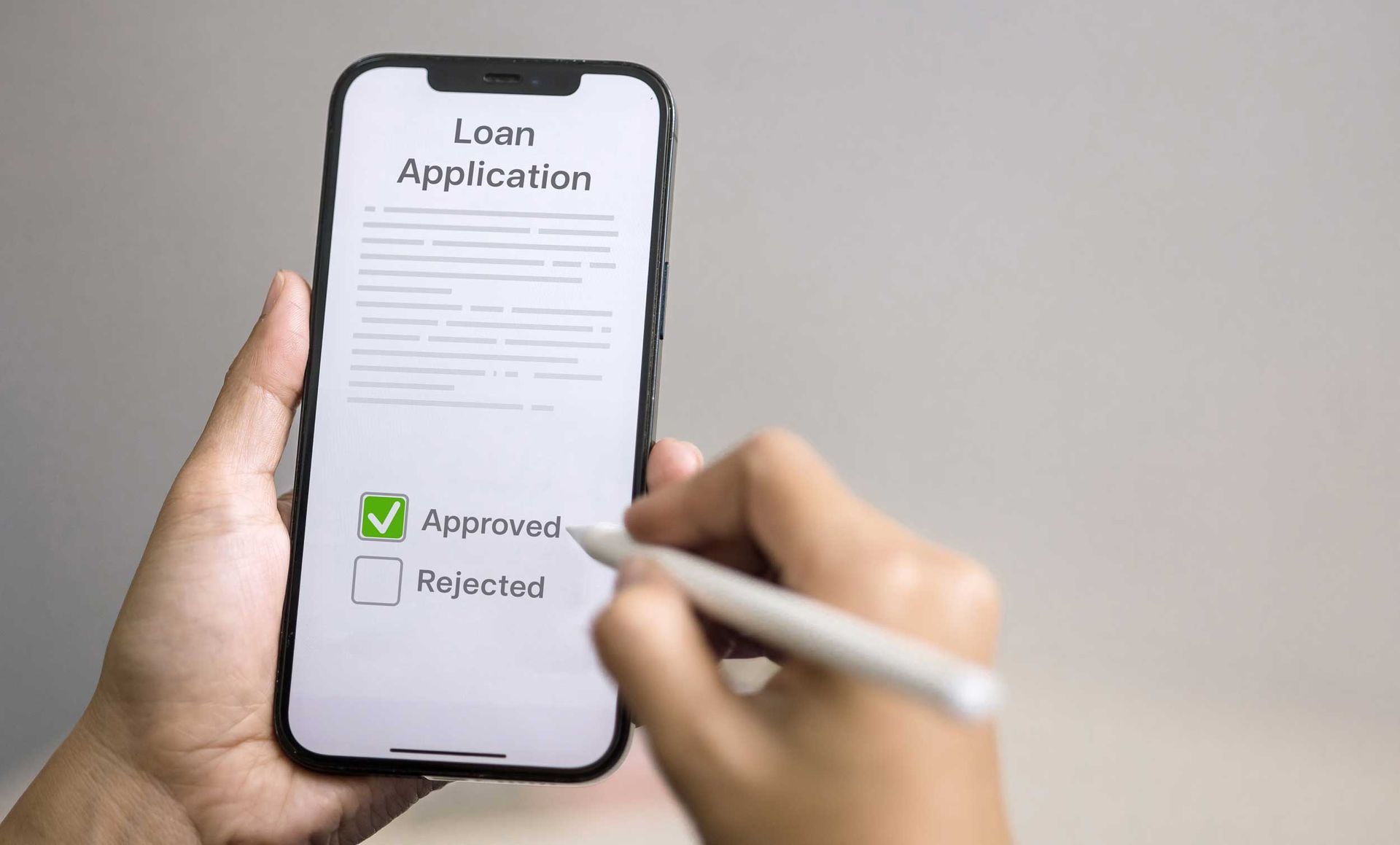 Person reviewing a loan application on a smartphone showing an approved status.