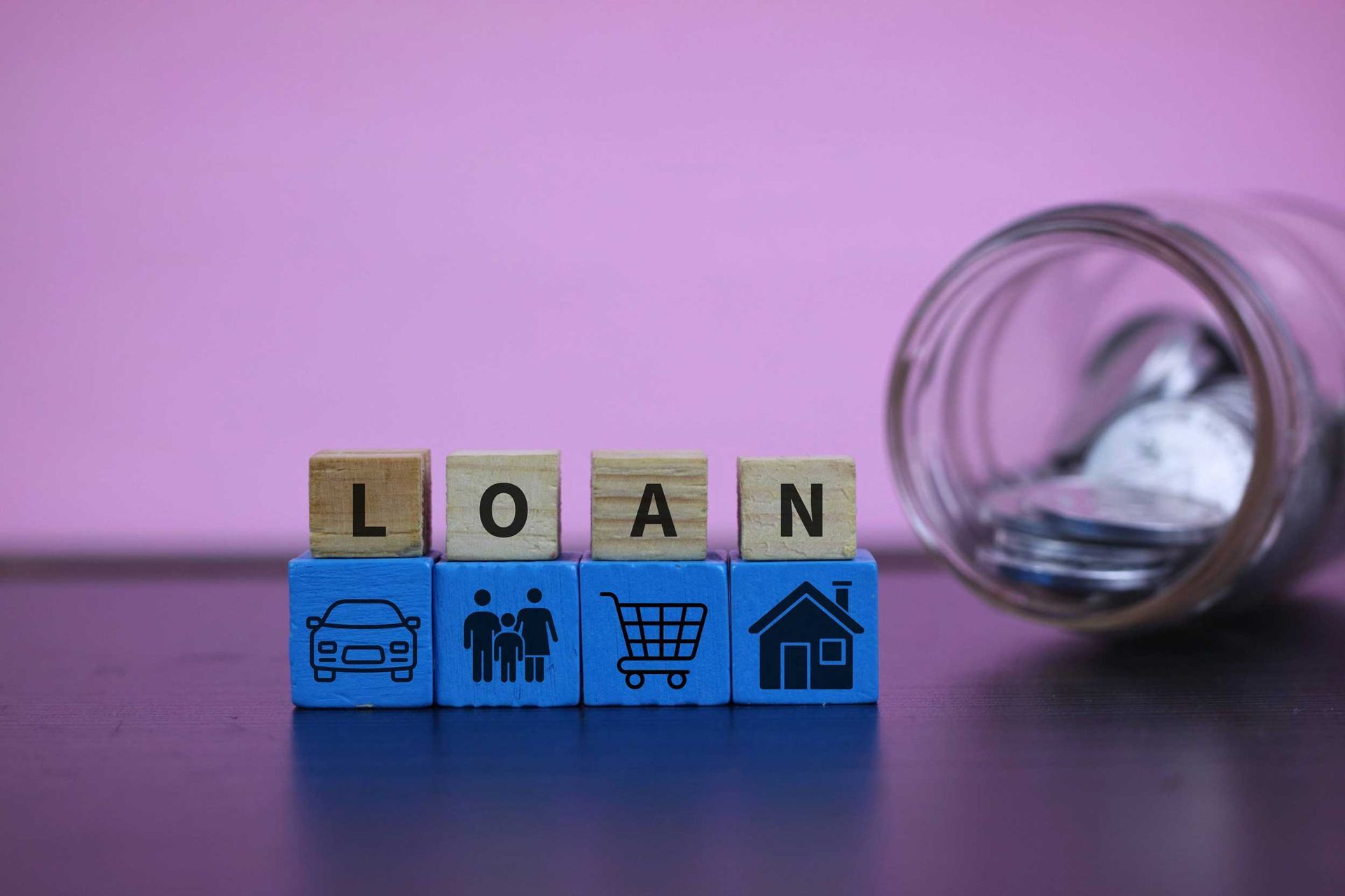 Wooden blocks spelling “loan” with icons for car, family, shopping, and home. Wooden blocks spelling “loan” with icons for car, family, shopping, and home.