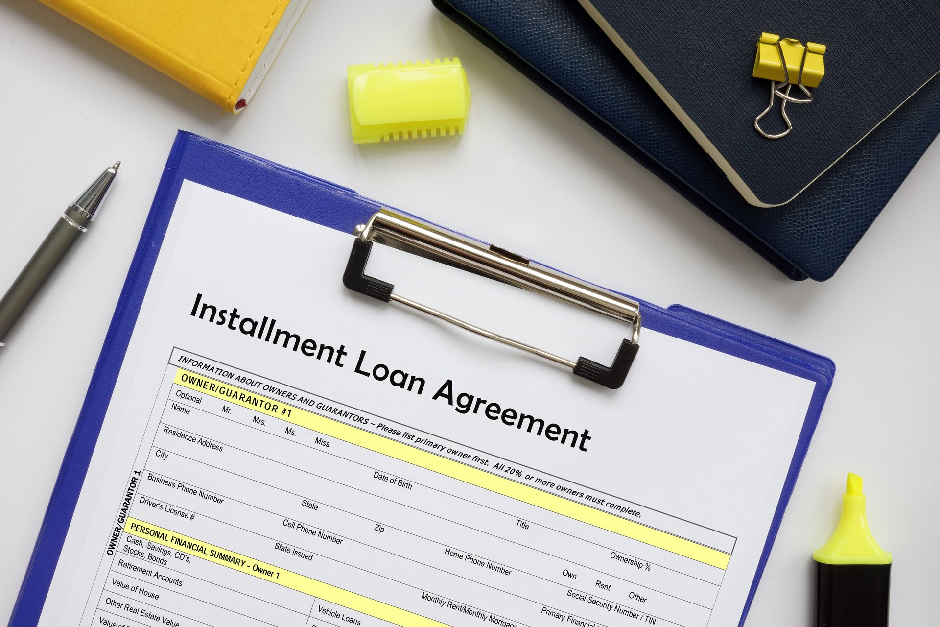 Installment loan agreement on clipboard with financial documents.
