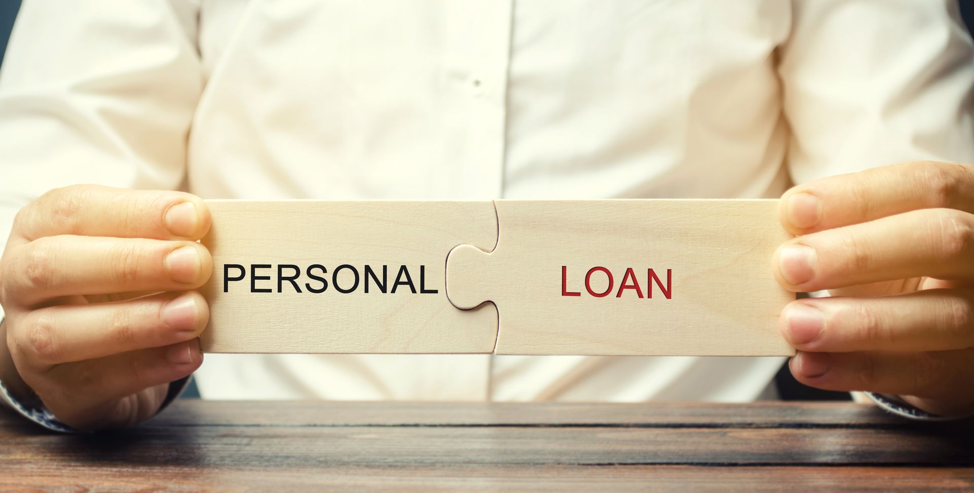 A man collects wooden puzzles with the word Personal Loan.