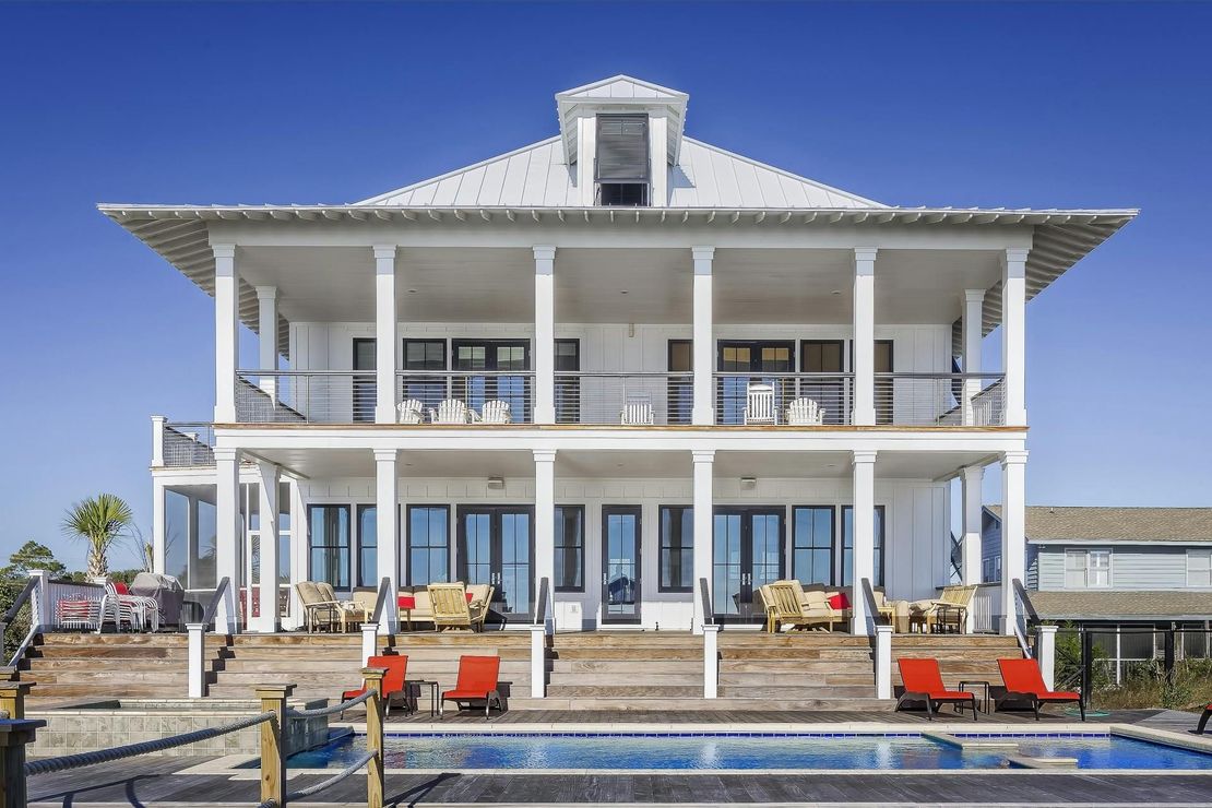 A large white house with a swimming pool in front of it.