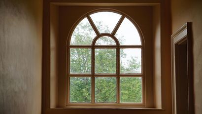 An arched window with a view of trees in a hallway