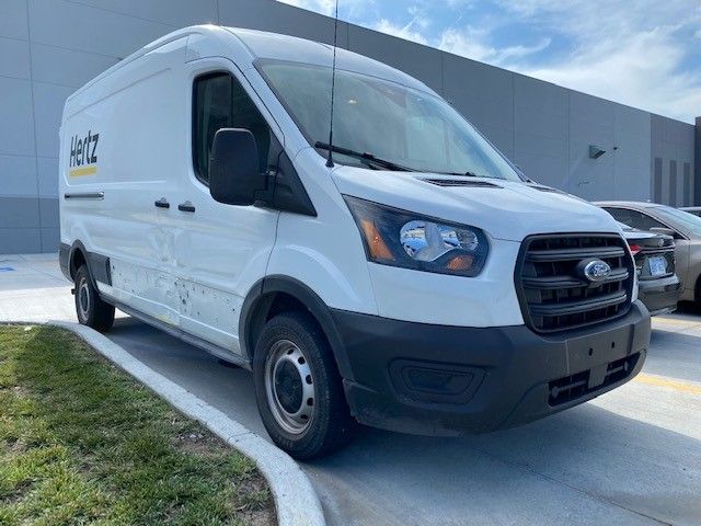 A white van is parked in a parking lot in front of a building.