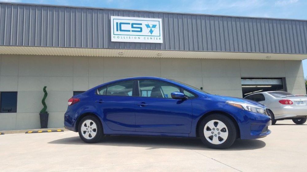 A blue car is parked in front of a building.