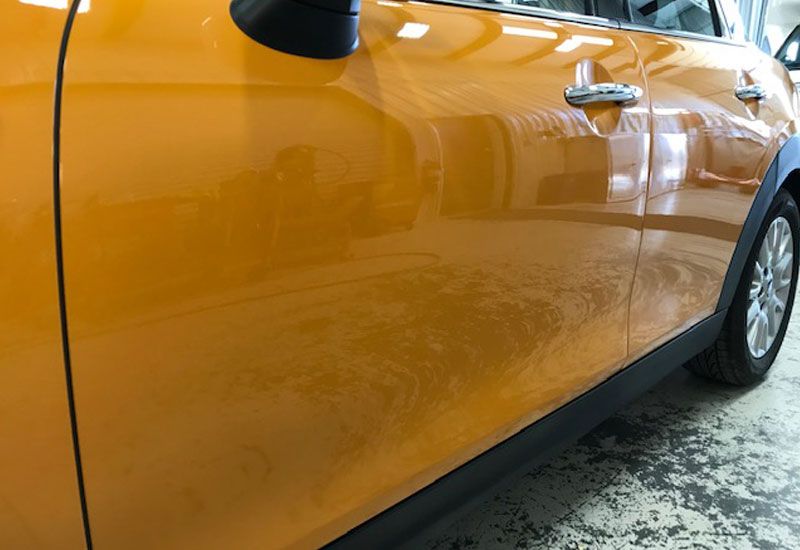 A close up of an orange car door in a garage.
