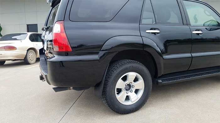 A black suv is parked in a parking lot next to a white car.