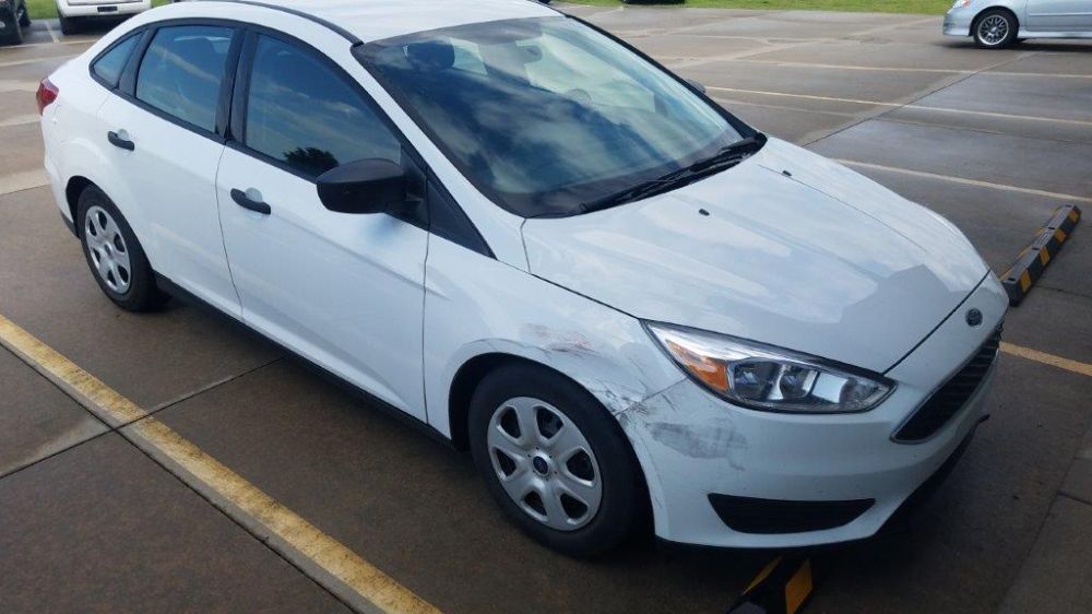 A white ford focus is parked in a parking lot.