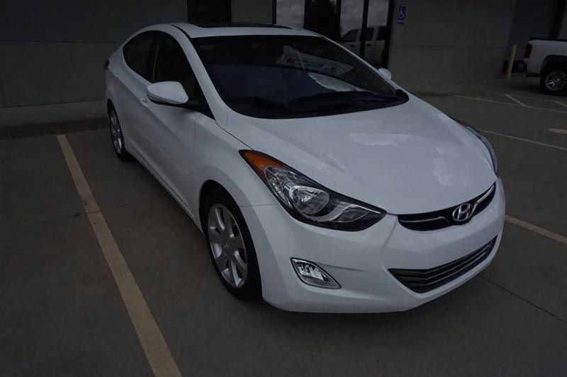 A white hyundai elantra is parked in a parking lot.