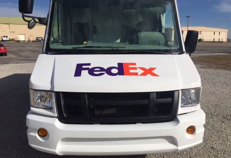 A white fedex van is parked in a parking lot