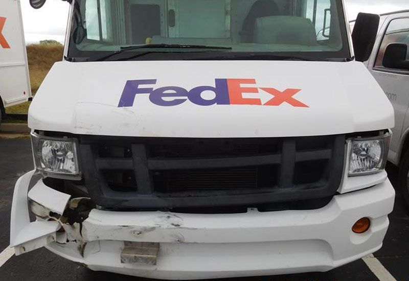 A white fedex truck with a damaged front end