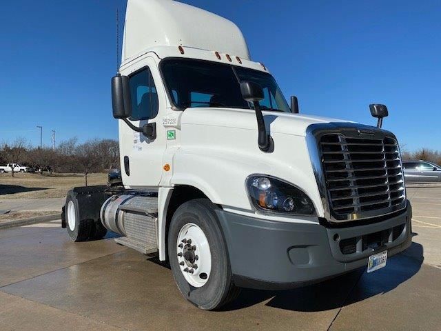 A white semi truck is parked on the side of the road.