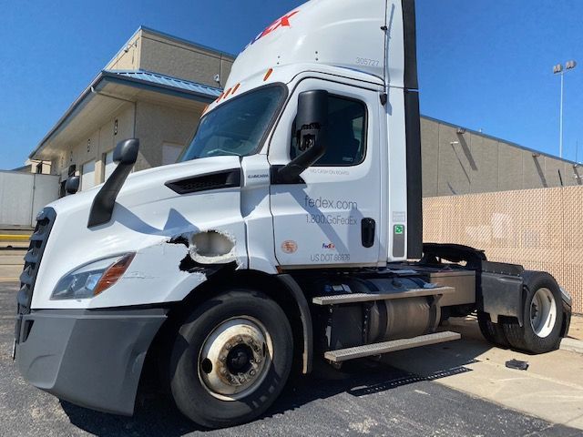 A white semi truck is parked in front of a building.