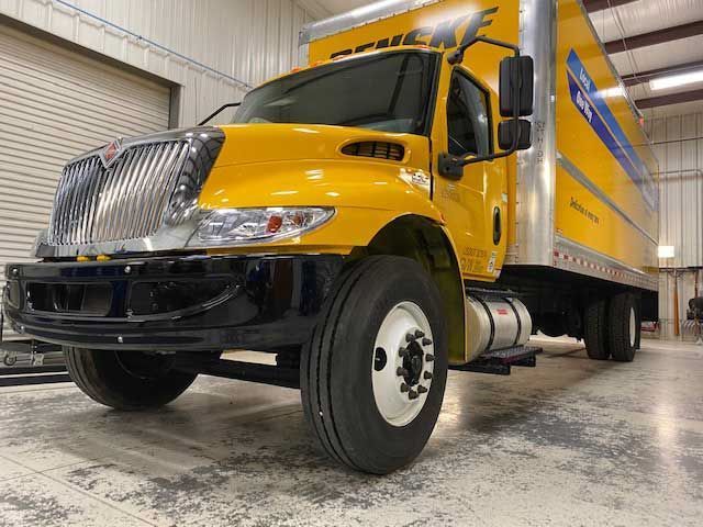 A yellow box truck is parked in a garage.