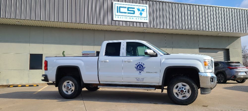 A white truck is parked in front of a building.