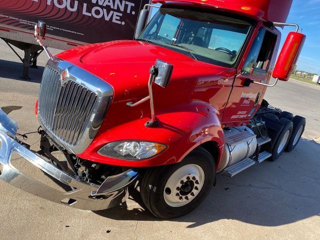 A red semi truck is parked next to a trailer that says 
