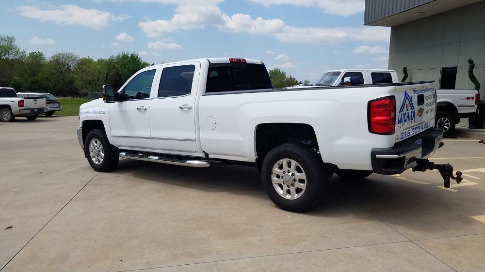 A white truck is parked in a parking lot next to a building.