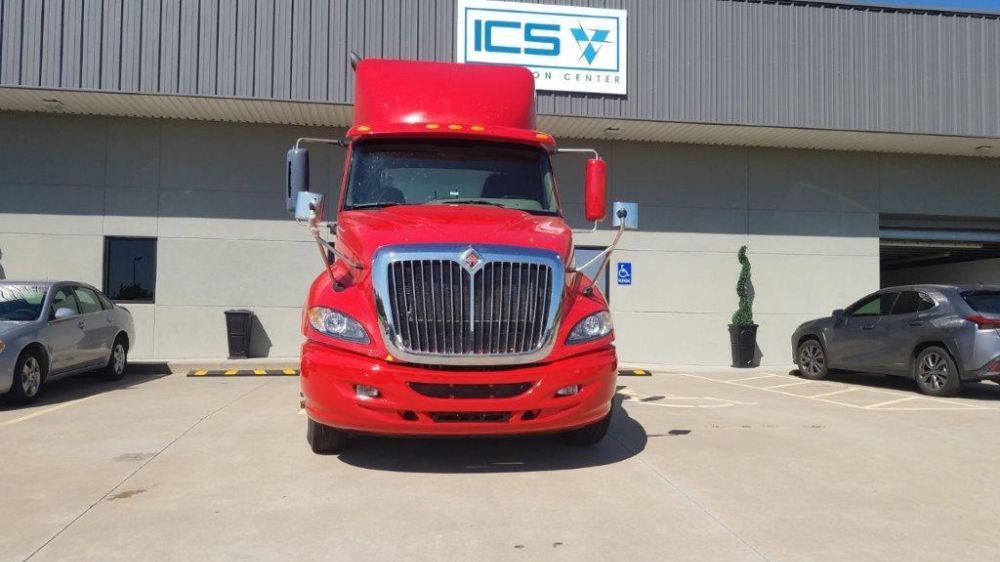 A red semi truck is parked in front of a building.
