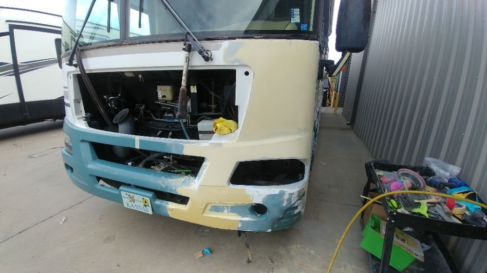 A rv is being repaired in a garage with the hood open.