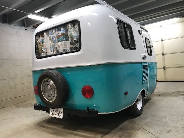A blue and white trailer is parked in a garage.