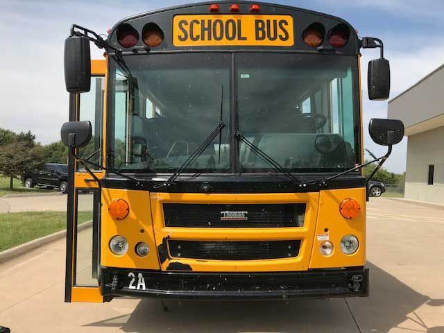 A yellow school bus is parked in front of a building.