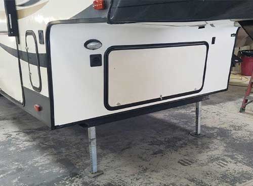 The back of a rv is sitting on the ground in a garage.