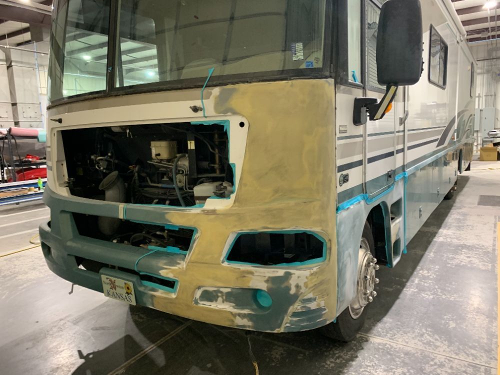 A large rv is being painted in a garage.