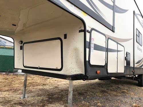 A white rv is parked in a dirt field.