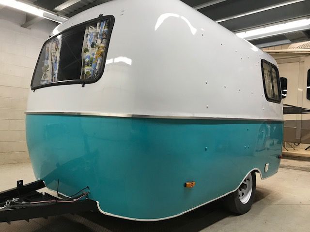 A white and blue trailer is parked in a garage.