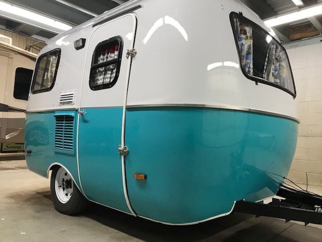 A blue and white trailer is parked in a garage.