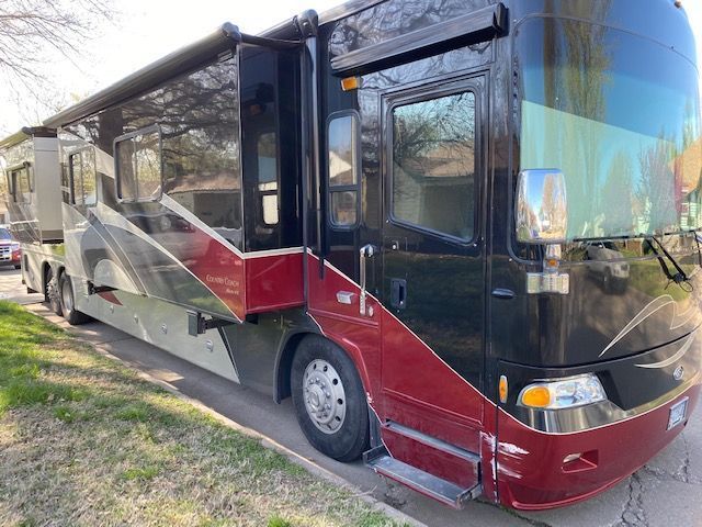 A large red and black rv is parked on the side of the road.