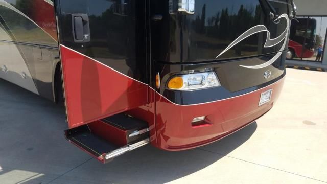 A red and black bus is parked in a parking lot.