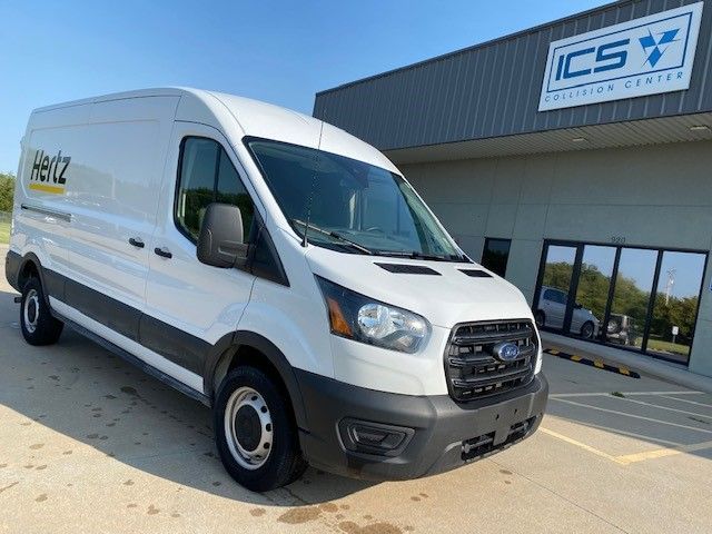 A white hertz van is parked in front of a building.