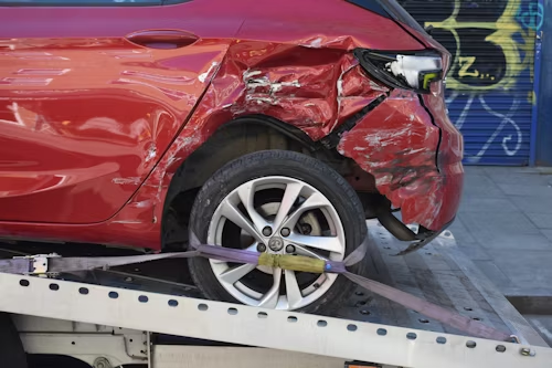 A red car is being towed by a tow truck.