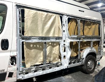 A white van is being remodeled in a garage.