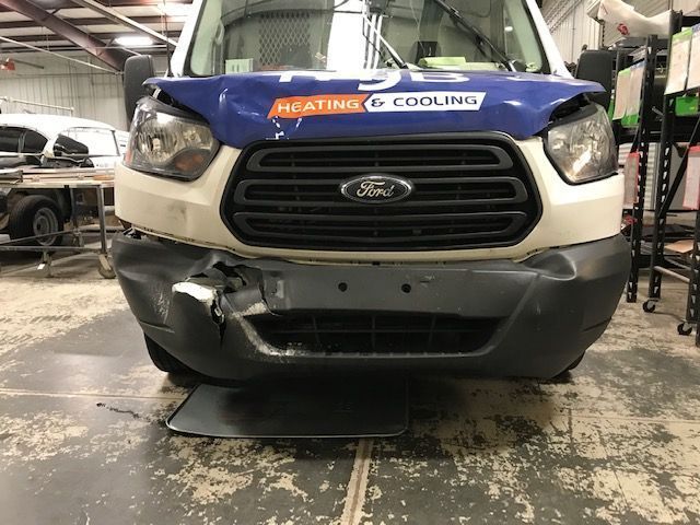 A ford van with a damaged front bumper in a garage
