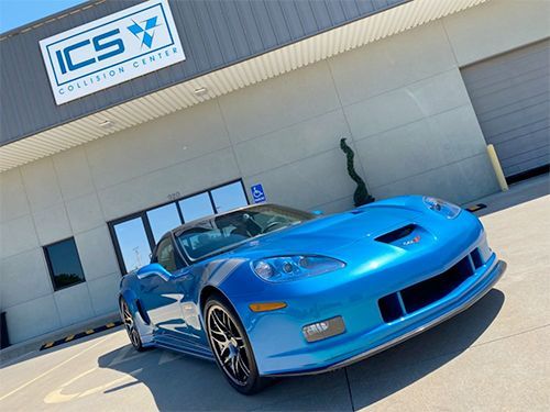 A blue sports car is parked in front of a building.