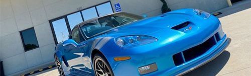 A blue sports car is parked in front of a building.