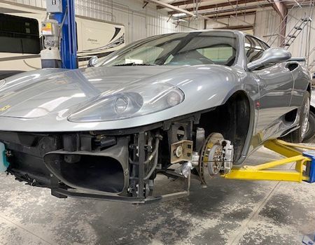 A silver sports car is sitting on a lift in a garage.