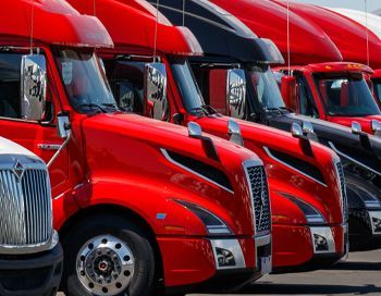 A row of red semi trucks are parked next to each other