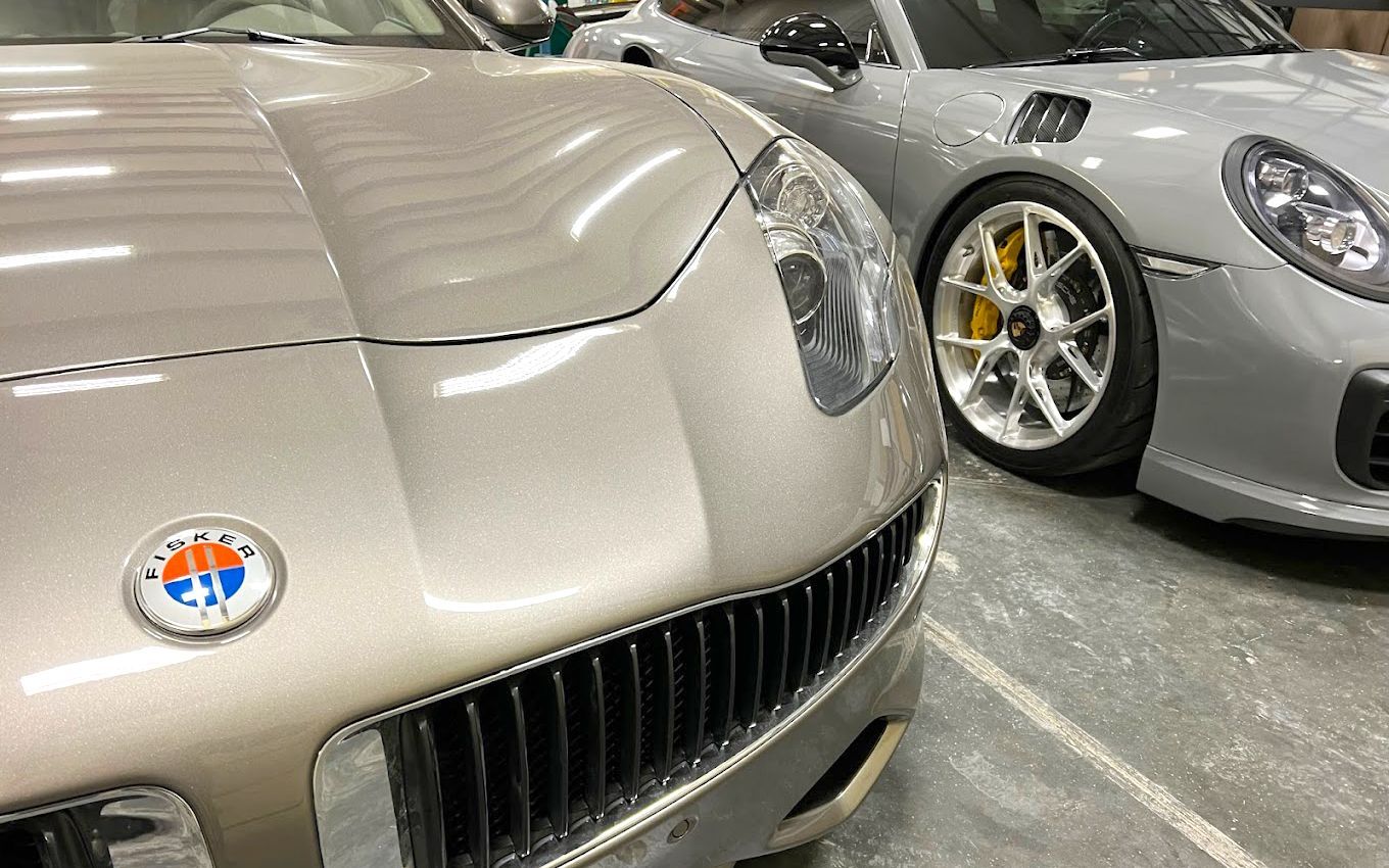 Two sports cars are parked next to each other in a garage.