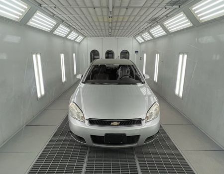 A woman is working on a car in a garage.