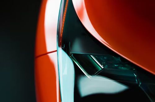 A close up of a red car 's headlight on a black background.
