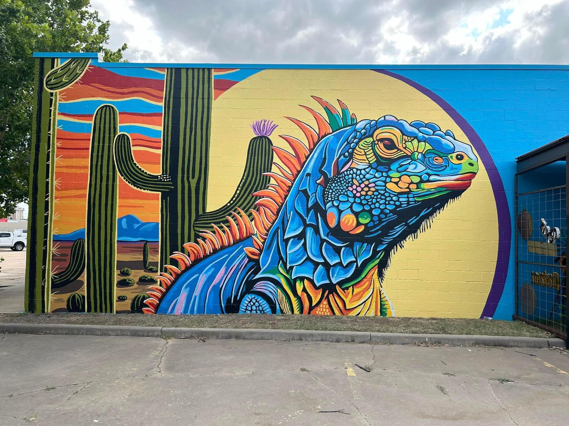 A colorful mural of an iguana and cactus on the side of a building.